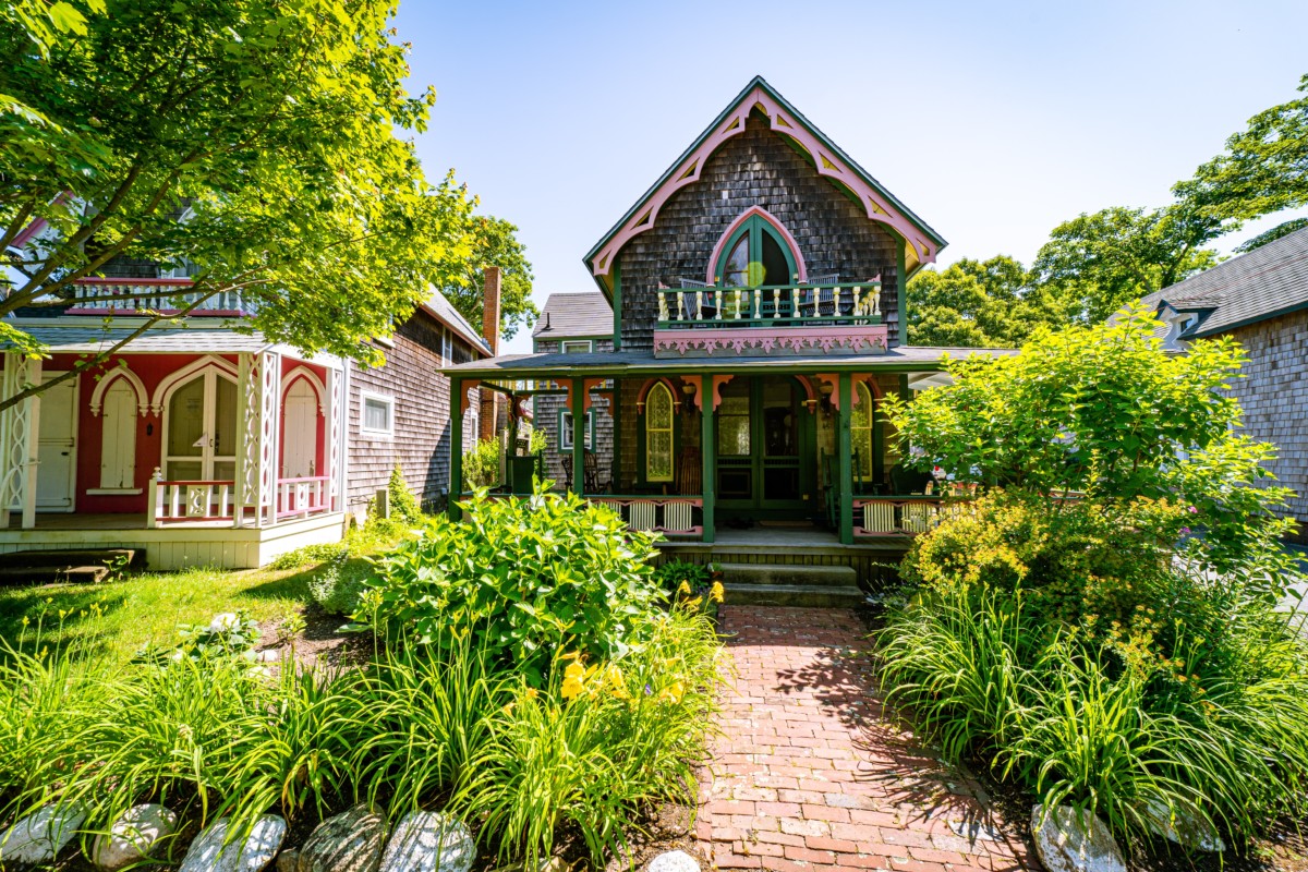 maison victorienne de style néo-gothique avec de la verdure dans la cour avant et des garnitures aux couleurs vives sur la maison