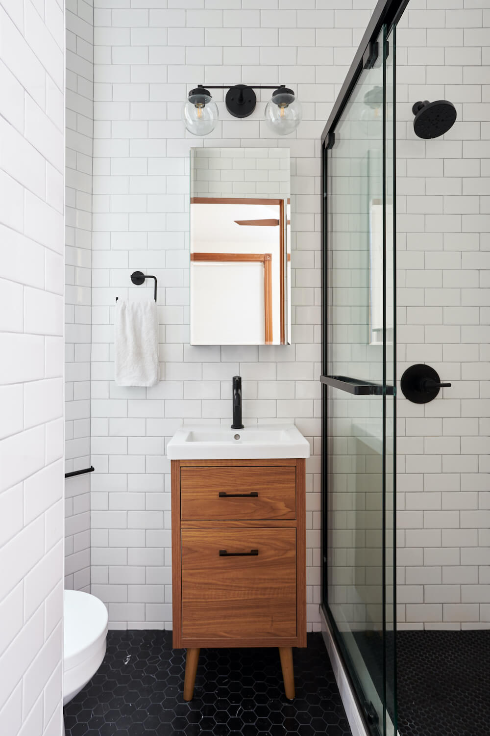 Salle de bain avec carrelage blanc, carrelage noir et douche vitrée