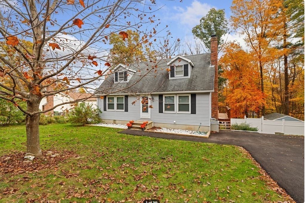 Maison Blue Cape Cod avec volets noirs et cheminée centrale à l'automne