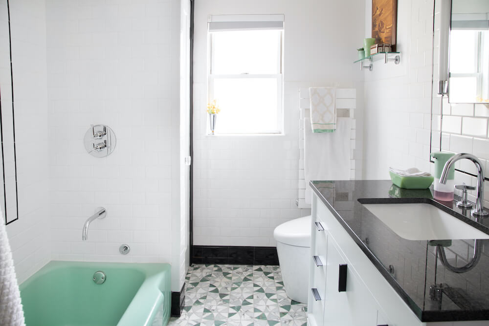 Salle de bain carrelée blanche avec des accents noirs et verts