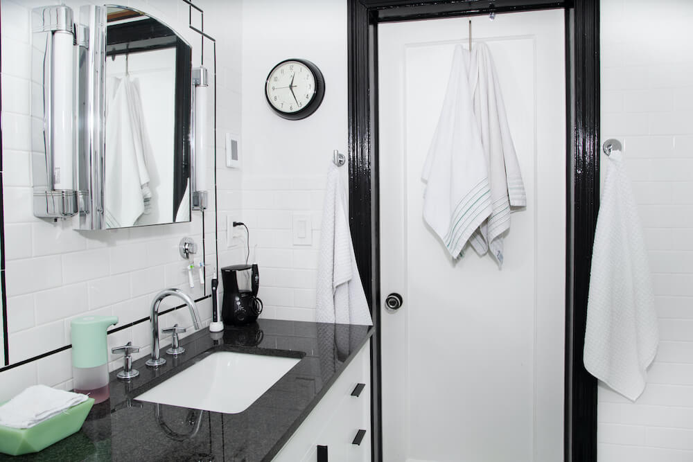 Salle de bain carrelée blanche avec des accents noirs