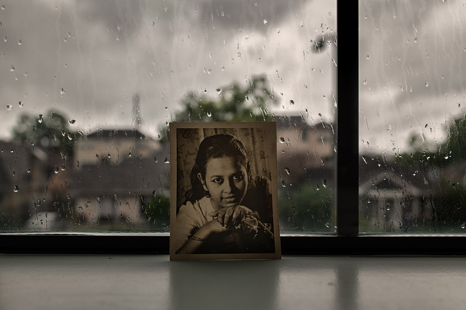 Une photographie de la mère de Rashed Haq contre une fenêtre avec des gouttes de pluie dessus